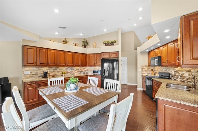 kitchen with sink, high vaulted ceiling, light stone counters, tasteful backsplash, and black appliances