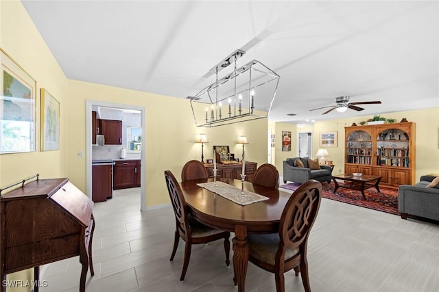 dining space featuring ceiling fan with notable chandelier