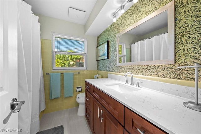 bathroom featuring vanity, tile walls, and toilet