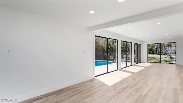 unfurnished room featuring beam ceiling and light wood-type flooring