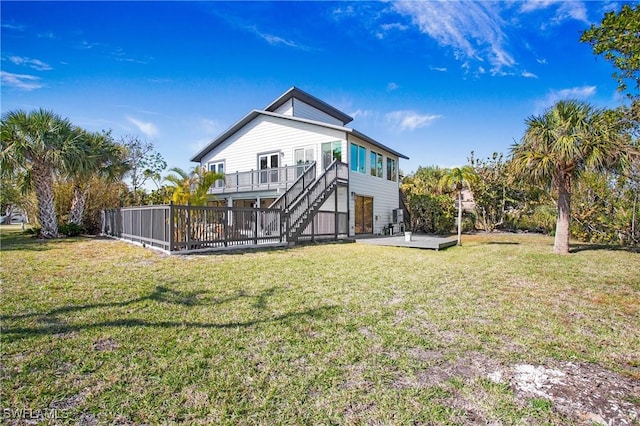 rear view of house with a wooden deck, a lawn, and a patio