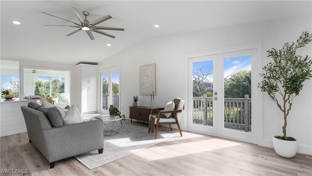 living room featuring lofted ceiling, french doors, ceiling fan, and light wood-type flooring