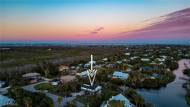 aerial view at dusk featuring a water view