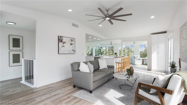 living room featuring ceiling fan, vaulted ceiling, and light hardwood / wood-style flooring