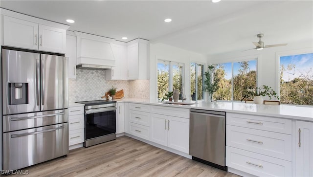 kitchen with stainless steel appliances, premium range hood, sink, and white cabinets