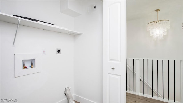 laundry room featuring hookup for a washing machine, hardwood / wood-style flooring, hookup for an electric dryer, and a notable chandelier