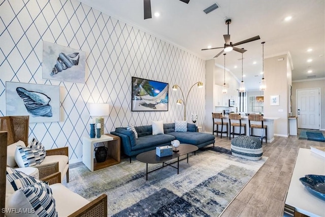 living room featuring crown molding, ceiling fan, and light wood-type flooring