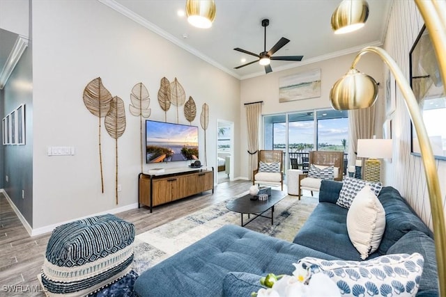 living room featuring hardwood / wood-style flooring, ceiling fan, ornamental molding, and a high ceiling