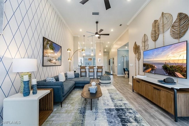 living room with ceiling fan, ornamental molding, and light hardwood / wood-style floors