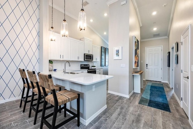 kitchen featuring a breakfast bar, decorative light fixtures, ornamental molding, electric range, and kitchen peninsula