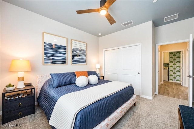 bedroom with washer / dryer, light colored carpet, ceiling fan, and a closet