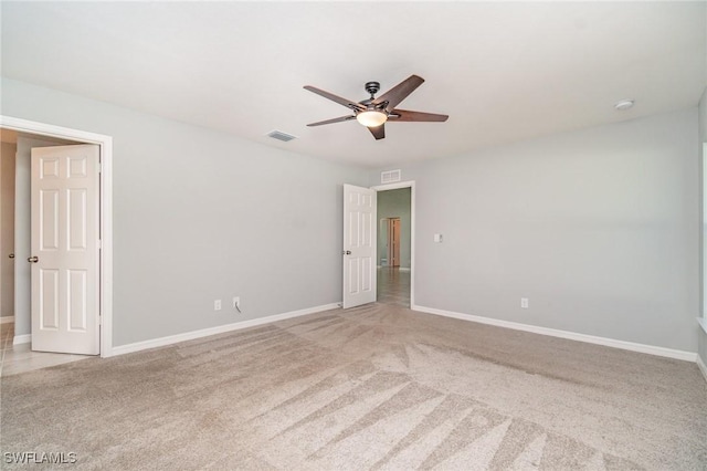 spare room with baseboards, visible vents, a ceiling fan, and light colored carpet