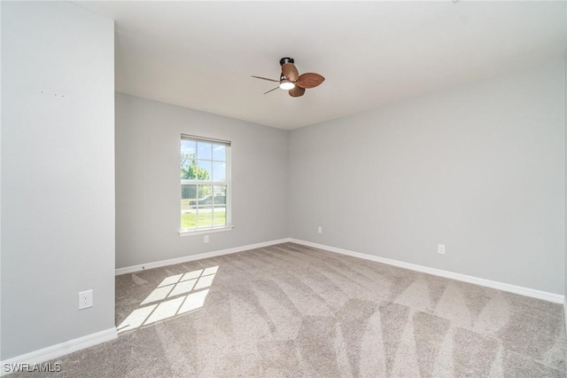 carpeted spare room with ceiling fan and baseboards