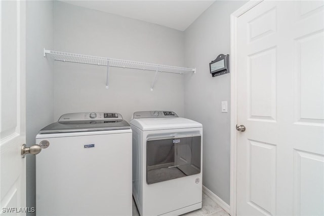 clothes washing area with laundry area, washing machine and clothes dryer, and baseboards