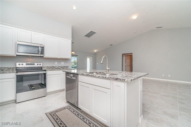 kitchen with appliances with stainless steel finishes, white cabinetry, vaulted ceiling, a sink, and light stone countertops