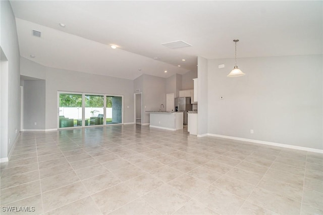 unfurnished living room with high vaulted ceiling, visible vents, and baseboards