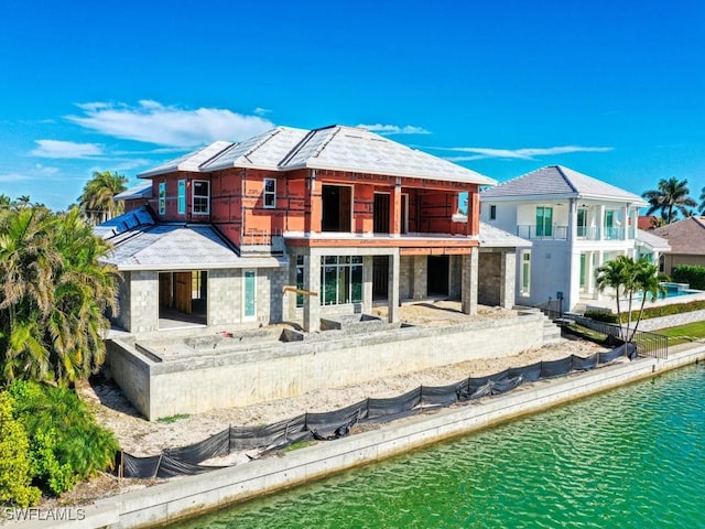 rear view of property with a balcony and a water view