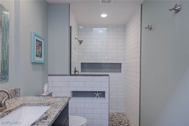 bathroom with vanity, toilet, and tiled shower