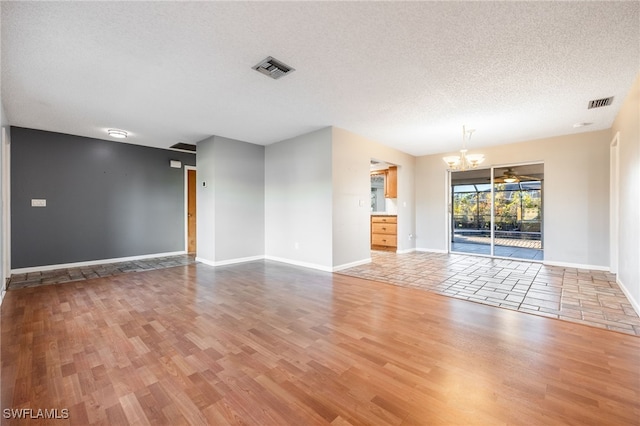 unfurnished living room featuring wood-type flooring, a textured ceiling, and a notable chandelier