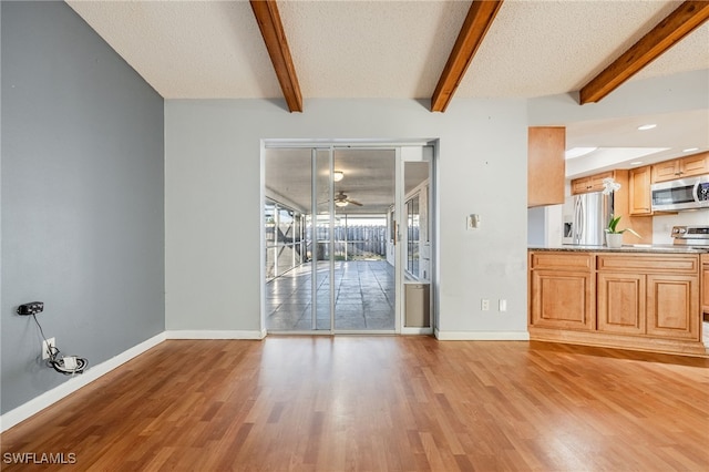 unfurnished living room with ceiling fan, beam ceiling, light hardwood / wood-style floors, and a textured ceiling