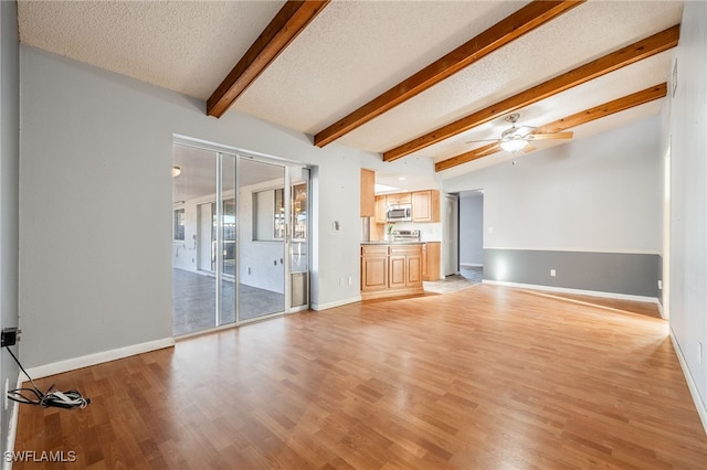 unfurnished living room featuring vaulted ceiling with beams, light wood-type flooring, a textured ceiling, and ceiling fan