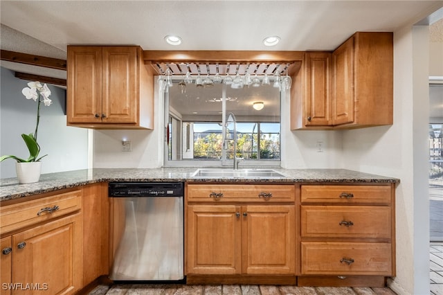 kitchen featuring stainless steel dishwasher, sink, and dark stone countertops