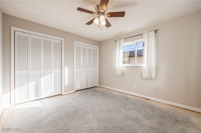 unfurnished bedroom with multiple closets, ceiling fan, concrete flooring, and a textured ceiling