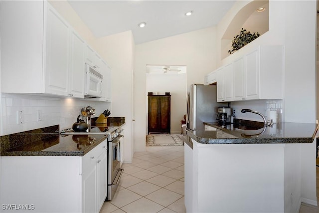 kitchen with light tile patterned floors, a peninsula, appliances with stainless steel finishes, and white cabinetry