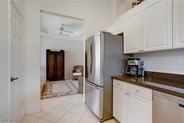 kitchen featuring stainless steel appliances, a raised ceiling, backsplash, a ceiling fan, and white cabinetry