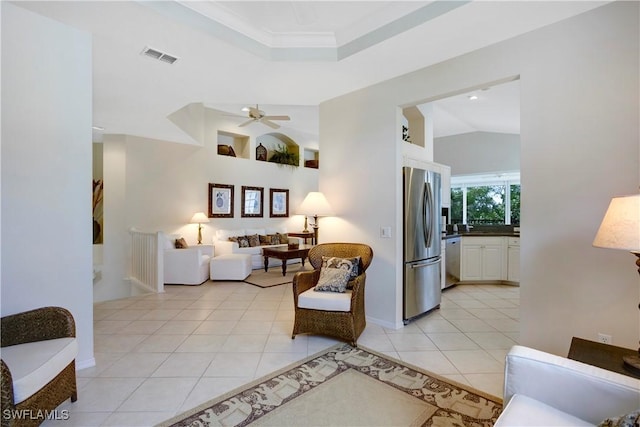 sitting room with light tile patterned floors, a raised ceiling, visible vents, a ceiling fan, and vaulted ceiling