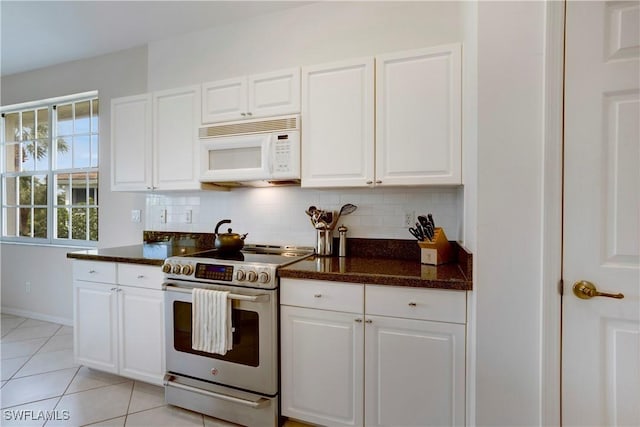 kitchen featuring white microwave, light tile patterned flooring, stainless steel range with electric stovetop, and tasteful backsplash