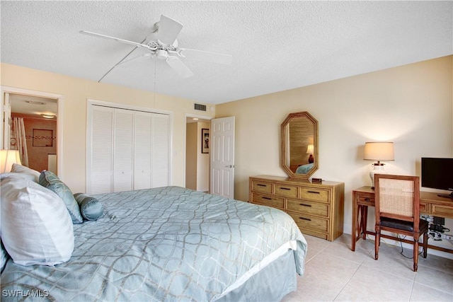 tiled bedroom featuring ceiling fan, a closet, and a textured ceiling