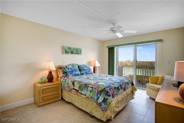 tiled bedroom featuring access to exterior, ceiling fan, a textured ceiling, and a water view