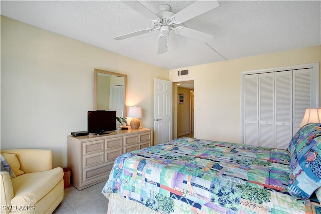 bedroom with ceiling fan, light tile patterned floors, a closet, and a textured ceiling