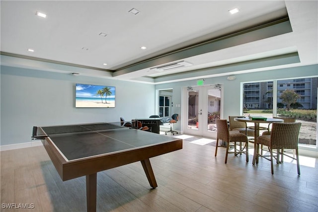 recreation room with french doors, a raised ceiling, and light hardwood / wood-style floors