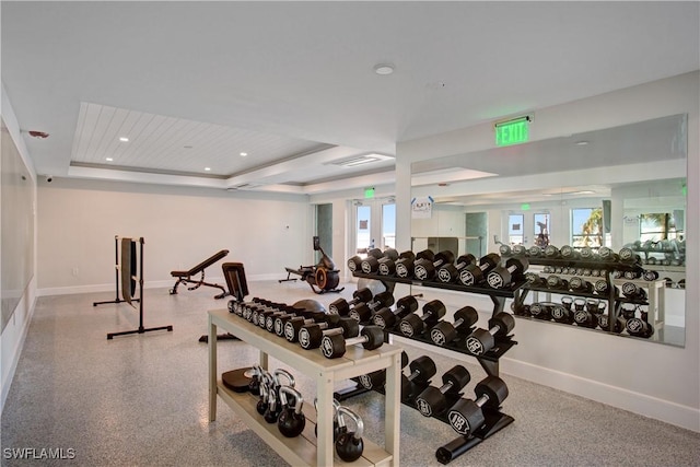 workout area with a raised ceiling and french doors