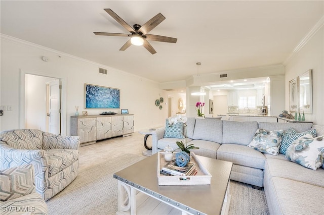 carpeted living room with ornamental molding, sink, and ceiling fan