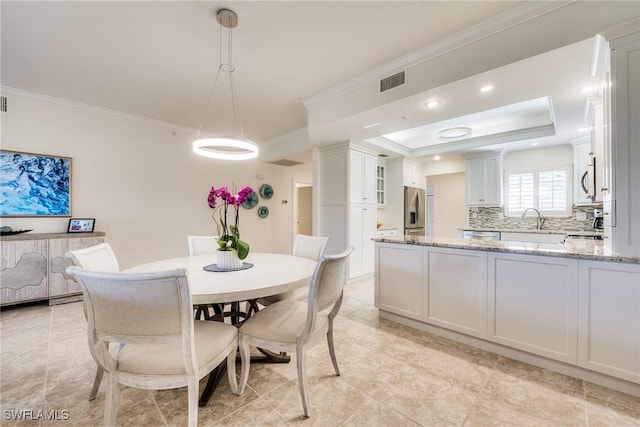 dining room with crown molding, a tray ceiling, and sink