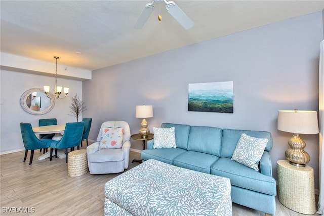 living room featuring ceiling fan with notable chandelier and light hardwood / wood-style flooring