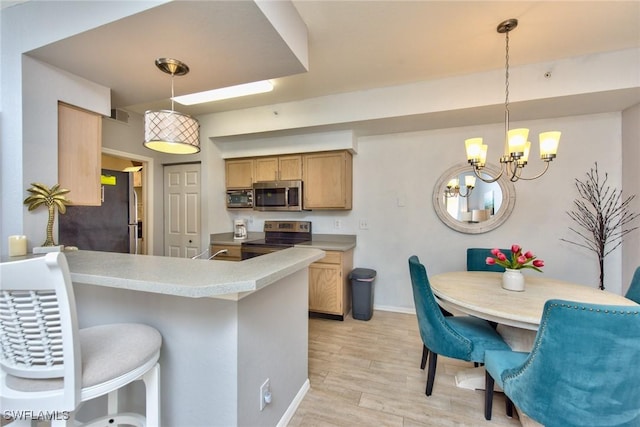 kitchen with pendant lighting, stainless steel appliances, kitchen peninsula, and light hardwood / wood-style flooring