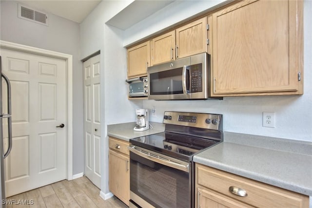 kitchen featuring light brown cabinetry, stainless steel appliances, and light wood-type flooring