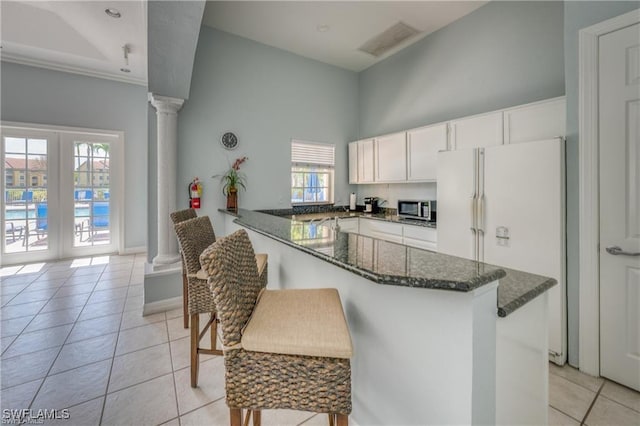 kitchen with ornate columns, white cabinetry, white refrigerator, light tile patterned floors, and kitchen peninsula