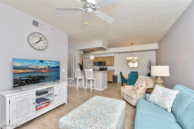 living room featuring ceiling fan with notable chandelier and light hardwood / wood-style flooring