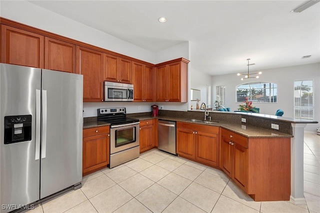 kitchen with light tile patterned flooring, sink, hanging light fixtures, kitchen peninsula, and stainless steel appliances