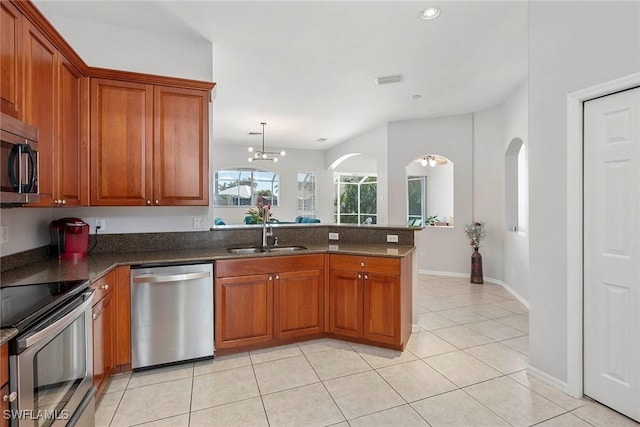 kitchen with appliances with stainless steel finishes, decorative light fixtures, sink, light tile patterned floors, and kitchen peninsula