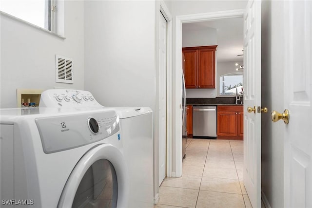 laundry area with light tile patterned floors, sink, and washing machine and clothes dryer