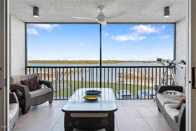 sunroom / solarium with a water view and ceiling fan