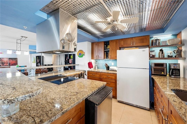 kitchen with white refrigerator, island exhaust hood, light tile patterned floors, and light stone counters