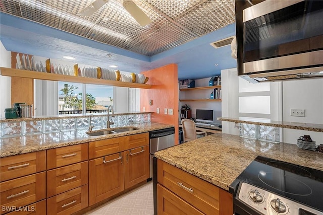 kitchen with light stone counters, ceiling fan, appliances with stainless steel finishes, and sink