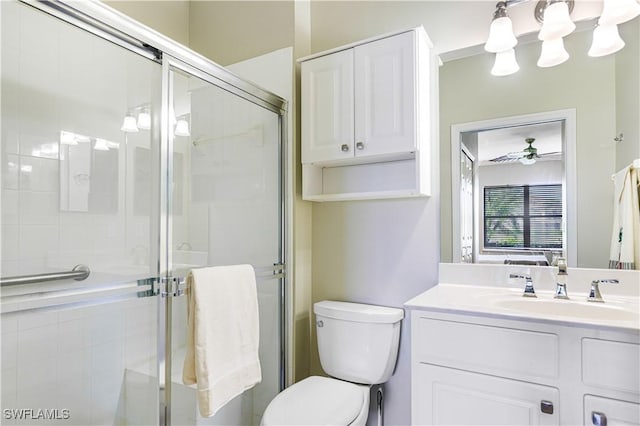 bathroom with ceiling fan, vanity, toilet, and a shower with shower door